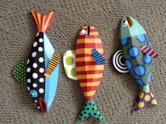 three colorful fish are on the floor next to each other and one is painted with polka dots