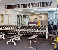 an empty gym with rows of dumbs and benches in front of a sign that says, strongder than westerday