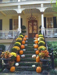 pumpkins and gourds line the front steps of a large house with white pillars