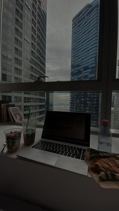 an open laptop computer sitting on top of a desk in front of a large window