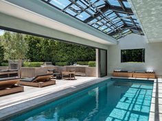 an indoor swimming pool with lounge chairs and sunroofing area next to it