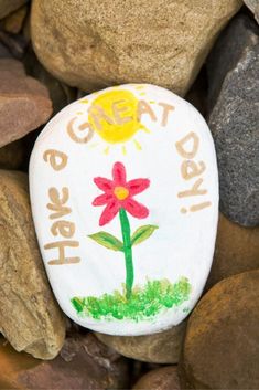 a painted rock sitting on top of rocks covered in grass and flowers with the words go eat healthy