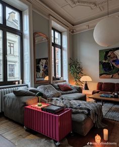 a living room filled with furniture and lots of windows next to a large painting on the wall