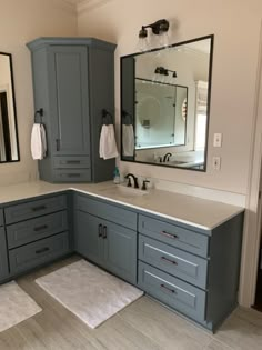 a bathroom with gray cabinets and white counter tops