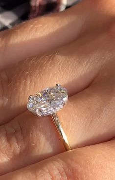 a close up of a person's hand with a diamond ring on their finger