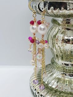 Gemstone dangle earrings Gemstone Chandelier Earrings.  Total length 9cm Beautiful Handcrafted,  Wire wrapped earrings. With Freshwater pearls. Amethyst. Ruby, Rose Quartz and Czech glass Crystal Beads. And Gold Plated findings and ear hooks.  One of a kind. In colours of pinks. Purples  reds. Ruby Metaphysical Properties It has been associated with improved energy and concentration, creativity, loyalty, honor and compassion. Ruby is thought to be protective of home possessions and family. Ruby Crystal Dangle Earrings As Gift, Crystal Dangle Earrings With Charms For Party, Crystal Drop Earrings With Dangling Beads, Crystal Long Drop Earrings As Gift, Crystal Long Drop Earrings For Gifts, Dangle Crystal Earrings With Pearl Drop, Long Drop Crystal Earrings For Gift, White Crystal Long Drop Earrings, Handmade Briolette Earrings For Party