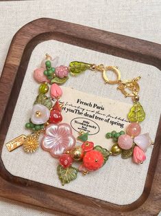 a wooden frame holding a bracelet with charms on it and a sign that says french paris