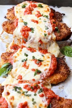 chicken parmesan with tomato sauce and basil leaves on top, sitting on a piece of parchment paper