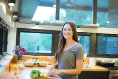 a woman is standing in the kitchen with her cutting board and vegetables on the counter