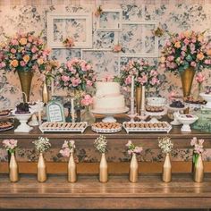 a table topped with lots of cakes and desserts next to vases filled with flowers