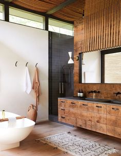 a bathroom with wooden floors and white walls, along with a large mirror on the wall