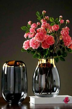 two vases with pink flowers in them on a table next to a book that reads art duo