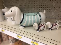 ceramic dog figurines are on the shelf in a store, one is blue and white