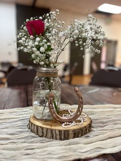 a mason jar with flowers in it sitting on top of a wooden table next to a horseshoe