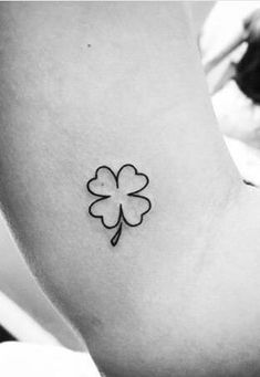 a small four leaf clover tattoo on the back of a woman's left arm