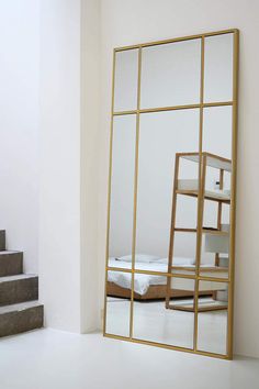 a mirror sitting on top of a white floor next to a stair case with a bed in it