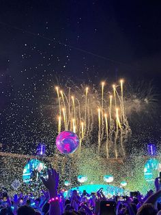 fireworks and confetti are being thrown over the crowd at a music festival with people holding up their hands