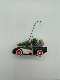 a toy car with grass growing out of it's back wheels on a white wall