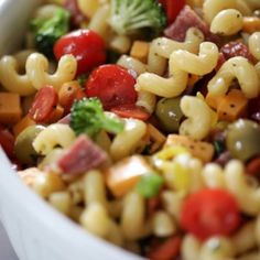 pasta salad with broccoli, tomatoes, and other vegetables in a white bowl