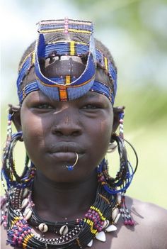 a woman from the african tribe with blue and gold jewelry on her face, wearing an elaborate headdress