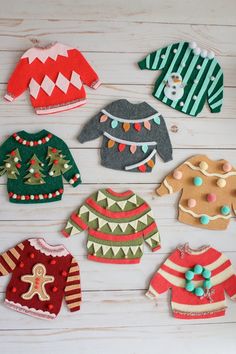 several knitted sweaters are arranged on a white table with christmas decorations and ornaments