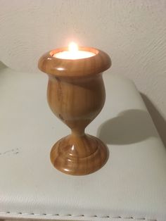 a small wooden candle holder sitting on top of a white chair next to a wall