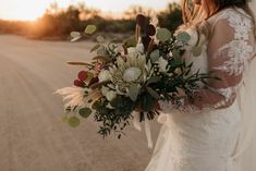 a bride holding her bouquet in the middle of the road at sunset or sunrise time