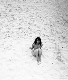 a woman sitting in the sand with her legs crossed