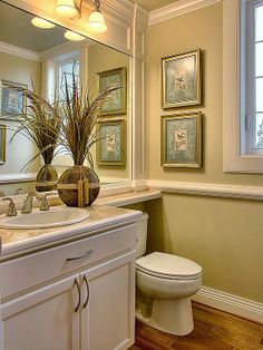 a white toilet sitting next to a bathroom sink under a mirror in a room with wooden floors