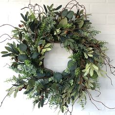 a wreath hanging on the wall with greenery