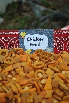 a bowl filled with cheetos sitting on top of a table next to a sign that says chicken feed