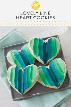 heart - shaped cookies with blue and green icing on a plate