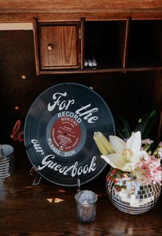 a record sitting on top of a table next to a vase with flowers in it