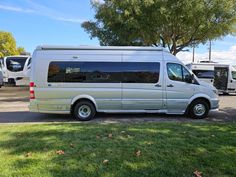 a silver van parked in a parking lot next to some trees and other rvs