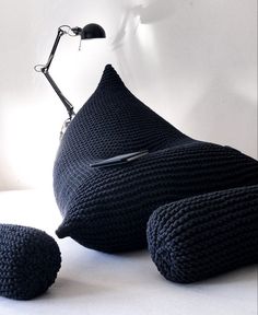 a black knitted bean bag sitting on top of a white table next to a lamp