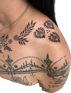 the back of a woman's shoulder with tattoos on her chest and arm,