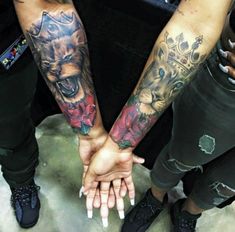 two people are holding hands with tattoos on their arms and one is holding the other's hand