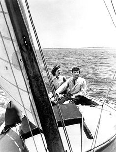 two men sitting on the bow of a sailboat