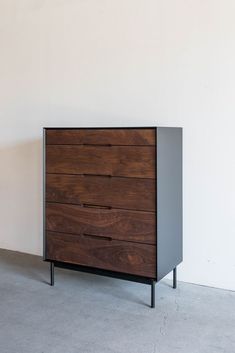 a wooden dresser sitting on top of a floor next to a white wall in a room