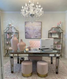 a desk with two stools and a laptop on it in a room that has a chandelier hanging from the ceiling