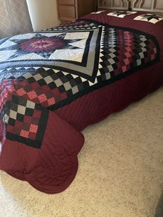 a bed with a red and black quilt on it