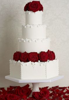 a three tiered white cake with red roses on top