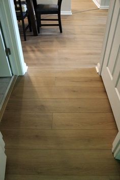 an open door leading to a dining room and living room with wood flooring in it