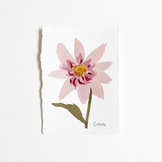 a pink flower with yellow center on a white background is featured in this image, it appears to be pressed onto a piece of paper