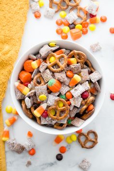 a bowl filled with candy cornflakes and pretzels on top of a table