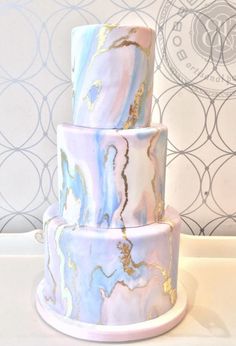 a three tiered cake with blue and gold marbled icing on it's sides