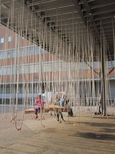 several people sitting on benches in front of a building with sticks attached to the roof