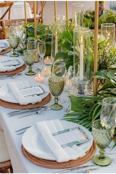 the table is set with place settings, candles and greenery for an elegant dinner