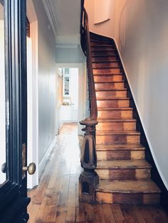 a wooden stair case next to a white wall and wood flooring in a house