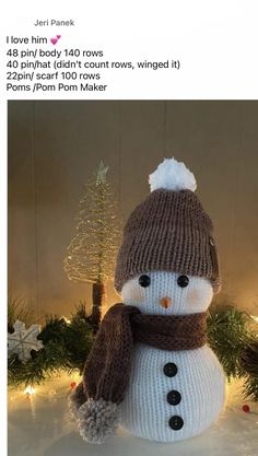 a knitted snowman sitting in front of a christmas tree